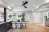 Open-concept interior featuring wood-finish flooring, recessed lighting, a modern ceiling fan, and a kitchen with a dark stone-top island and built-in