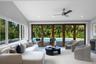Vaulted ceilings featuring recessed lighting, a modern ceiling fan, expansive multi-panel sliding glass doors, and large windows encompassing exterior