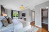 Natural wood flooring, custom built-in closet cabinetry and a window framing exterior foliage