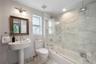 Full bathroom featuring a white porcelain pedestal sink, stone-patterned wall-to-wall shower surround with a frameless glass door, stone-patterned til