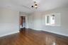 Room featuring wood-finish flooring, white plantation shutters, a multi-light chandelier, and a walk-in closet with built-in wooden shelving and drawe