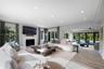 Open-concept living space featuring wood-finish flooring, recessed lighting, a stone-surround fireplace, and multi-panel glass doors