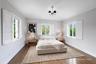 Light-filled room featuring wood-finish flooring, three windows with white plantation shutters