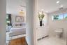 Bathroom featuring a white vanity with a marble countertop, white subway tile wall accents, and stone-finish floor tiling
