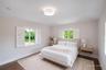 Room featuring wood-finish flooring, dual windows with plantation shutters, a neutral wall palette, and a circular flush-mount ceiling light
