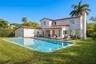 Mediterranean inspired exterior featuring a clay tile roof, stucco finish, in-ground swimming pool, wood-finish decking, and multi-panel folding glass