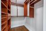 Walk-in closet featuring custom wood-finish shelving, integrated drawers, metal hanging rods, and wood-finish flooring