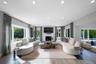 Living area featuring wood-finish flooring, recessed lighting, expansive multi-pane windows, and a central fireplace with a stone-finish surround