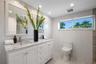 Double vanity with white cabinetry, stone-surface countertop, rectangular under-mount sinks, subway-tiled walls, and stone-finish flooring