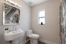 Pedestal sink with chrome faucet, multi-bulb vanity light, framed mirror, and toilet featuring a modern low-profile design