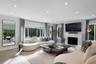 Spacious interior filled with natural light, featuring recessed lighting, stone-finish fireplace surround, large-format windows, and wood-finish porce
