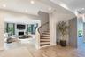 Curved staircase with wood treads and black metal handrail, fireplace with stone-surround, recessed lighting, and wood flooring