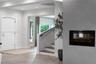 Foyer featuring recessed lighting, a recessed wall-mounted fireplace, a white arched-top entry door, and a staircase with wood-finish treads and a mat