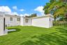 Backyard featuring a manicured lawn, perimeter masonry wall, detached storage structure, and exterior lighting fixtures