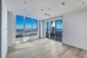 Open-concept interior featuring floor-to-ceiling windows, wood-finish flooring, custom cabinetry with stone-finish countertops, and an integrated kitc