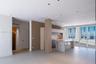 Custom kitchen featuring stone-slab waterfall island and countertops, natural wood-finish cabinetry, fluted wood wall paneling, and integrated under-c