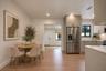 Kitchen featuring light-toned cabinetry, stainless steel refrigerator, stone countertops, and wood-finish flooring