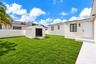 Aerial perspective featuring a manicured lawn, a detached structure, a paved driveway with turf ribbon accents, and perimeter landscaping