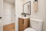Wood-finish vanity with a rectangular sink, matte black faucet, wall-mounted rectangular mirror with a black frame, and a coordinating matte black tow