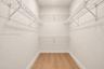 Walk-in storage space featuring wood-finish flooring and multi-level white wire shelving