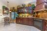 Kitchen featuring custom wood cabinetry with glass-front display uppers, stone-surface countertops, decorative metallic backsplash, a large wood-finis