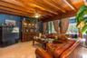 Exposed wood ceiling beams, stone flooring, floor-to-ceiling windows, and red brick wall detailing
