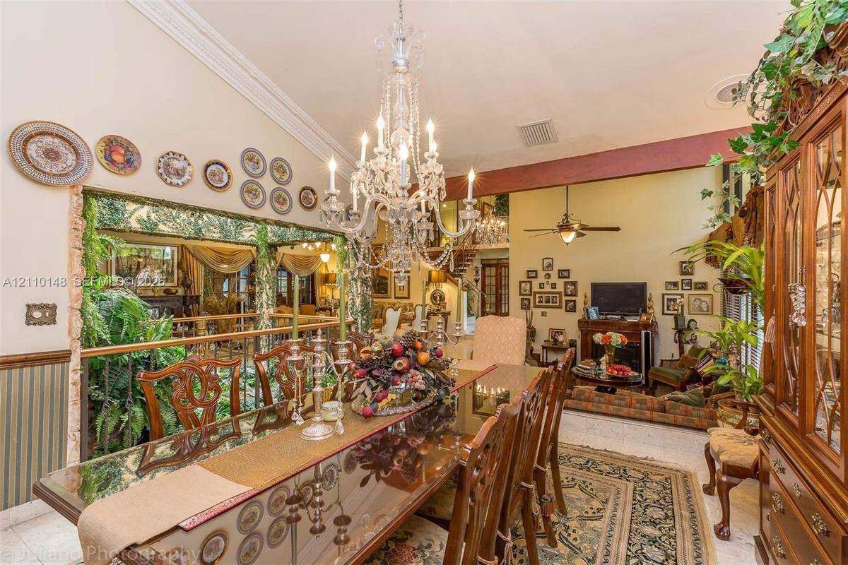 Vaulted ceiling featuring crown molding, prominent crystal chandelier, and integrated fireplace with brick surround