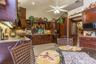 Kitchen featuring stained wood cabinetry, stone countertops, tiled flooring, vaulted ceilings, and a decorative door with glass detailing