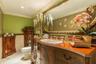 Custom dark-stained wood cabinetry vanity with patterned basin, expansive wall-mounted mirror with decorative frame, crown molding, and polished stone