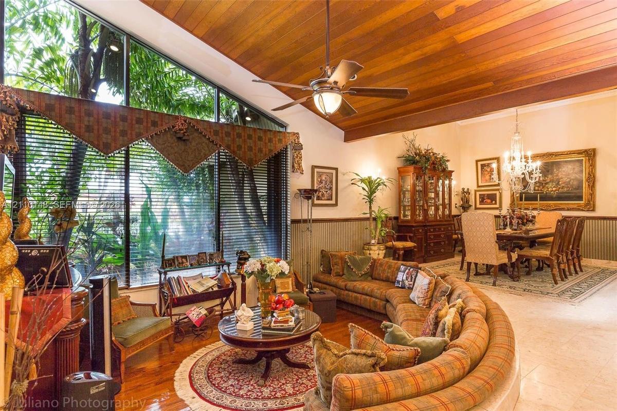 Vaulted tongue-and-groove wood plank ceiling, floor-to-ceiling windows, wood flooring, and a multi-arm chandelier