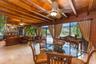 Expansive living area featuring exposed wood ceiling beams, stone flooring, red brick accent walls, and ceiling-mounted light fixtures