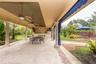 Covered patio featuring stone-tile flooring, decorative masonry columns, recessed ceiling fans, and a built-in outdoor kitchen with stone detailing
