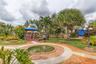 Landscaped backyard featuring a circular brick-paver fountain, wooden deck with overhead canopy, manicured lawn, established tropical foliage, and dec