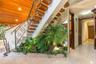 Open-tread staircase featuring wood-finish steps and custom metal scrollwork railing, wood-paneled ceiling, integrated interior planter with stone ele