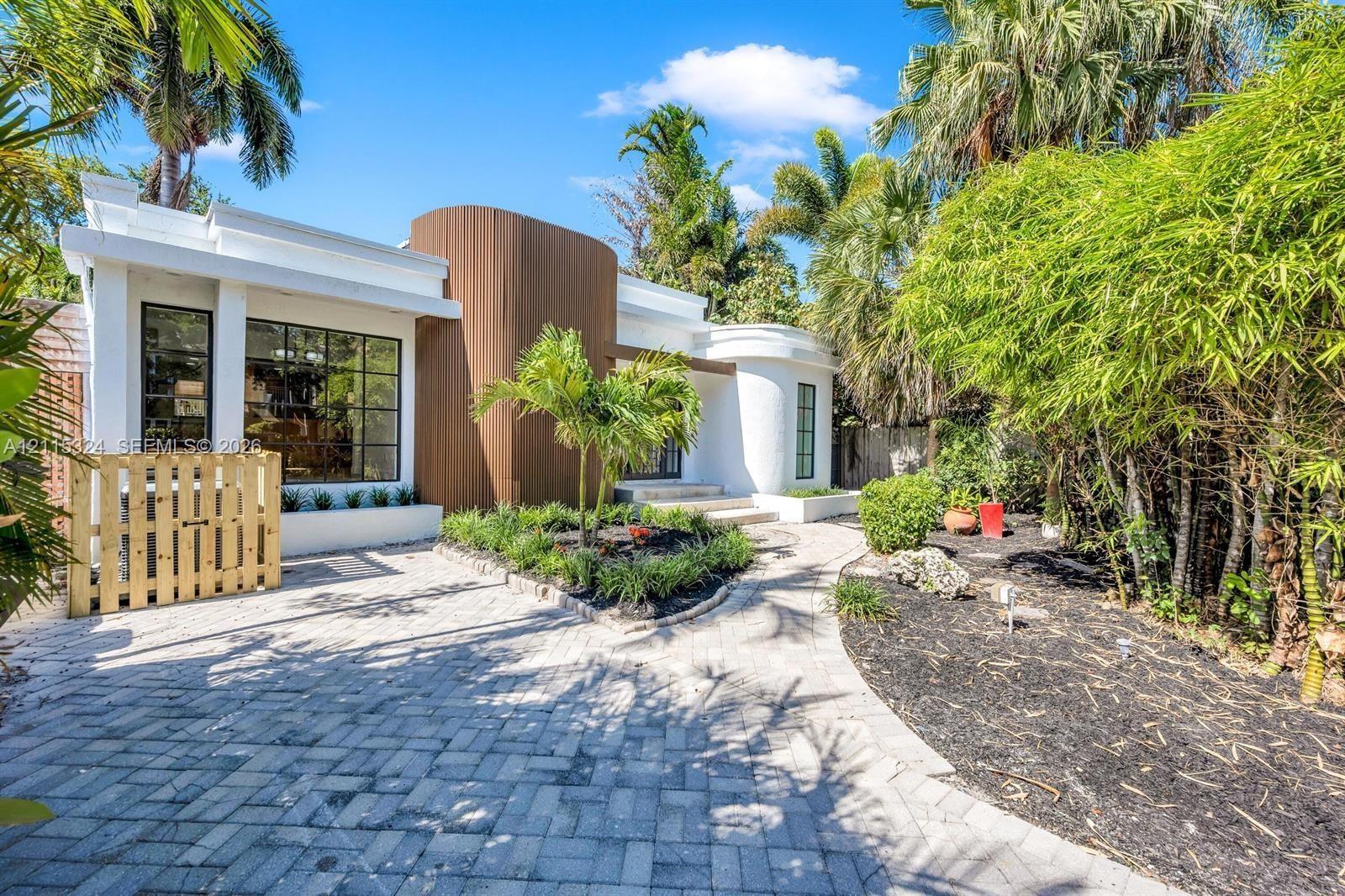 Contemporary exterior featuring curved architectural details, vertical wood-finish siding, white stucco facade, large multi-pane windows, and a paved 