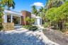 Contemporary exterior featuring curved architectural details, vertical wood-finish siding, white stucco facade, large multi-pane windows, and a paved 