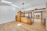 Vaulted ceilings featuring a skylight and circular accent window, wood-finish flooring, custom cabinetry with dark countertops, and a modern multi-pen