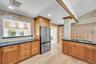 Kitchen featuring wood cabinetry, stone tile backsplashes, dark stone countertops, recessed lighting, and wood-finish flooring