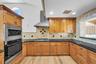 Kitchen featuring natural wood cabinetry, dark stone countertops, stainless steel wall-mounted oven and microwave, professional-style stainless steel 