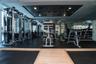 Fitness center with extensive equipment, rubber flooring, mirrored walls, and recessed lighting