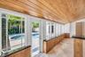 Sunroom featuring wood-plank ceiling, natural stone flooring, floor-to-ceiling windows, and built-in cabinetry with dark stone countertops