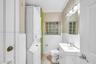 Combination laundry area and bathroom featuring a stacked washer and dryer, square glass block window, white vanity with integrated sink, and polished