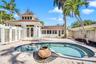 Custom-designed outdoor area featuring a swimming pool, integrated fountain, paver stone hardscaping, tiered architectural roofline, and glass block p