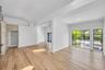 Interior featuring vaulted ceilings, wide-plank wood-finish flooring, floor-to-ceiling grid-style windows, and stone-surround wall accents