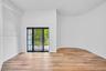 Interior space featuring wood-finish flooring, a curved wall, and a black-framed grid glass door with side lights
