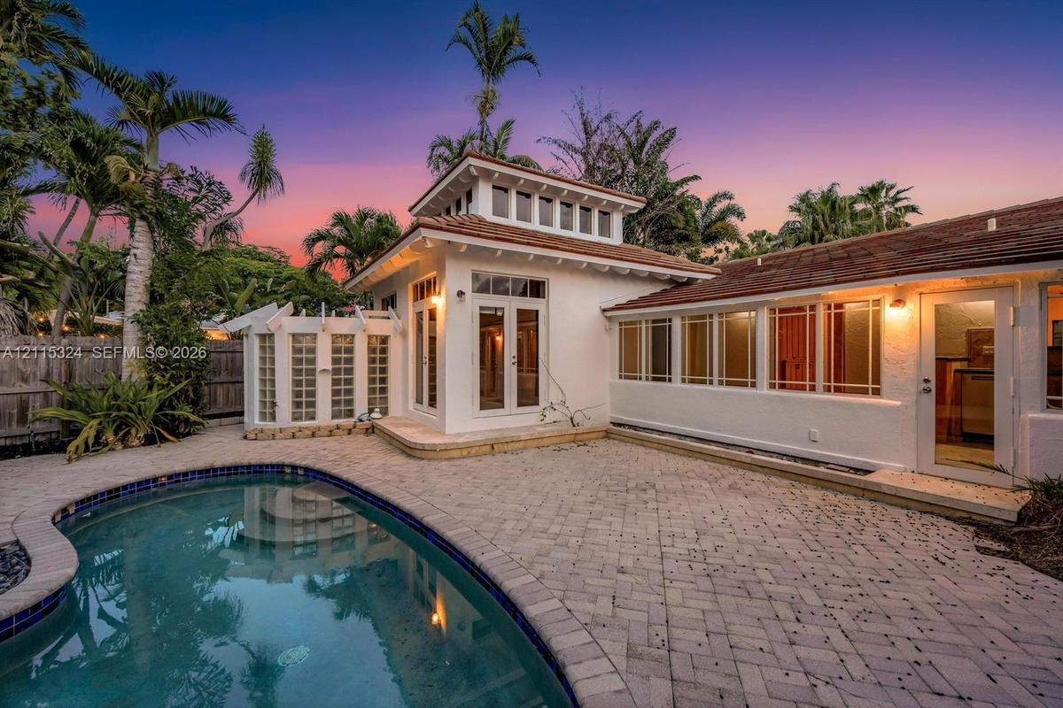 Exterior featuring a swimming pool, paved patio, stuccowork facade, cupola architectural element, and multi-light windows