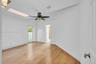 Interior space featuring wood-finish flooring, a vaulted ceiling with a skylight, a ceiling fan with integrated lighting, and an exterior glass-panel 