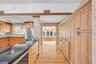 Custom cabinetry featuring wood-finish lower and full-height built-in storage, dark stone countertops, stainless steel undermount sink, and herringbon