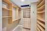 Walk-in closet featuring light wood-finish built-in cabinetry, floor-to-ceiling adjustable shelving, integrated garment rods, and five soft-close draw