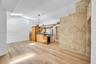 Vaulted ceilings featuring a skylight and circular window, wide-plank wood-finish flooring, full-height stone-finish accent wall, and cabinetry with i